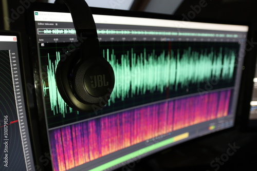 The photo shows headphones and in the back ground waveform in adobe audition. photo
