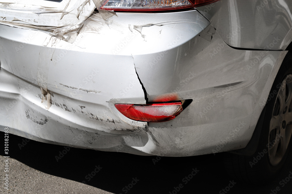 Closeup wrecked rear bumper and tail lights of new modern grey car