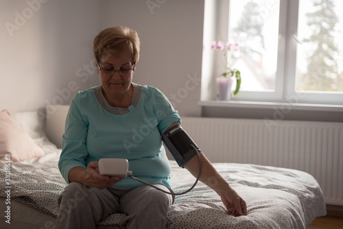 Senior woman checking blood pressure on a monitor  photo