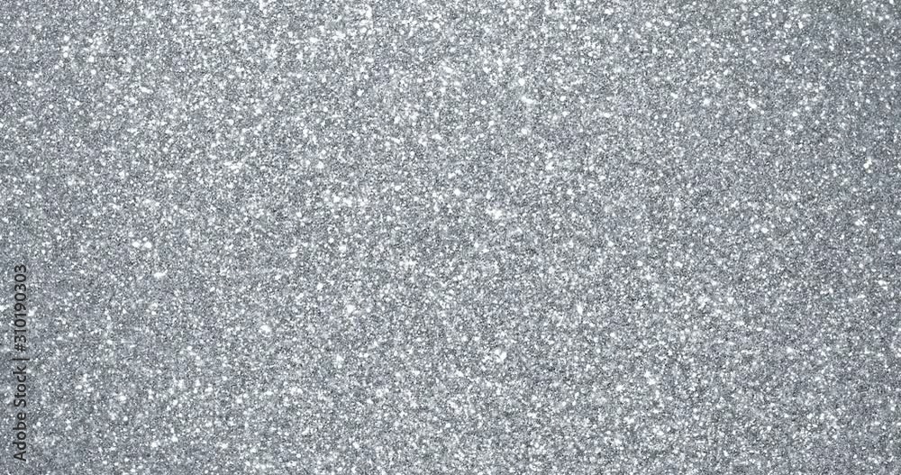 Silver glitter background with sparkling texture. Silver shimmering light, stars sequins sparks and glittering glow foil background