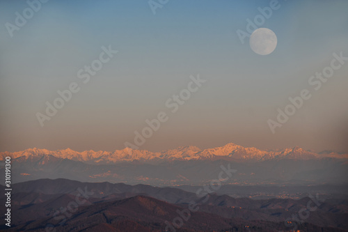 Il tramonto sulla catena di montagne con la luna piena