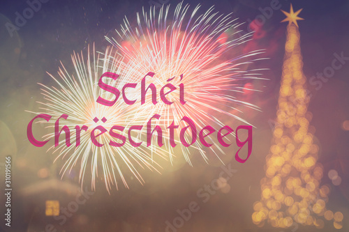 "Schéi Chrëschtdeeg" means "Merry Christmas" in Luxembourgish . Blurred background of decorated Christmas tree with golden lights. Fireworks. Bokeh. 25 December. 2020. Greeting card Luxembourg.
