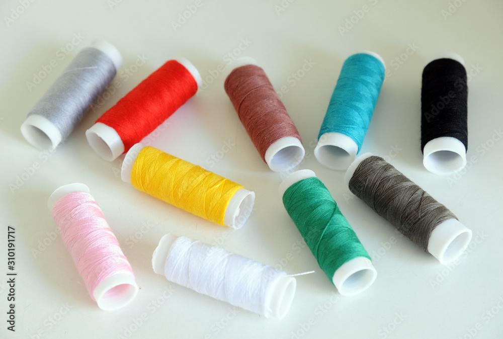 Accessories for tailoring on white table - Scissor , scissors, buttons, needle and thread, spools of colored threads Accessories for tailoring on white table - Scissor , scissors, buttons, needle and thread, spools of colored threads