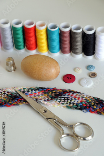 Accessories for tailoring on white table - Scissor , scissors, buttons, needle and thread, spools of colored threads