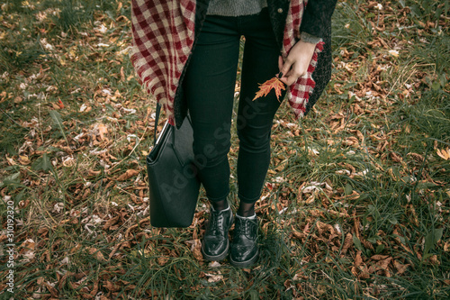 Girl stands and holds an autumn leaf photo