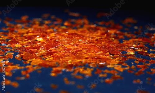 natural shellac flakes in a beam of light on a dark background