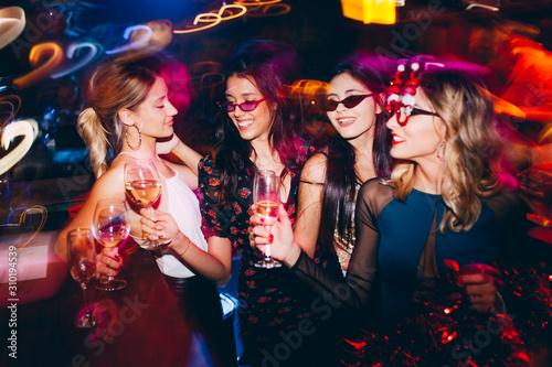 Group of female friends at club drinking wine and having fun. New year party