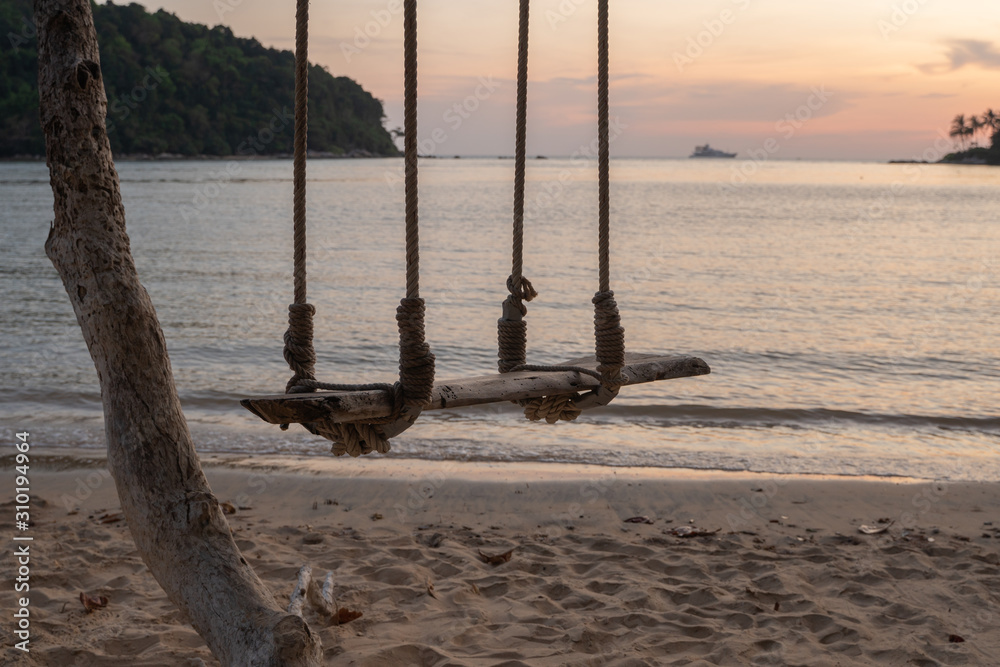 evening sun shining Sea wave on the sunset beach and Wooden swing hang under a tree evening sun shining Sea wave on the sunset beach and Wooden swing hang under a tree