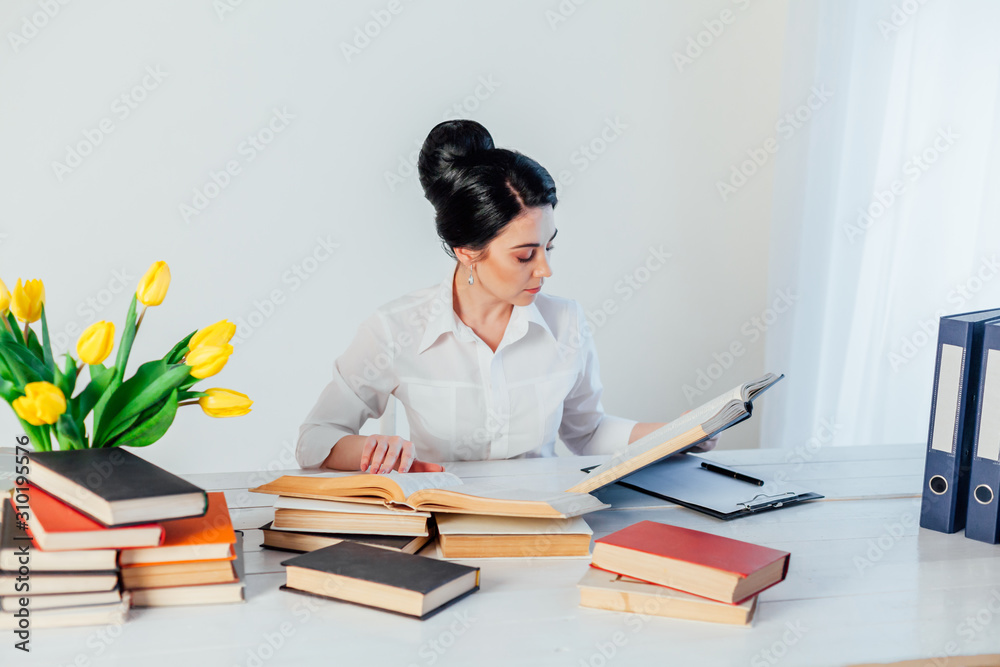 women in a business suit behind a table with books women in a business suit behind a table with books