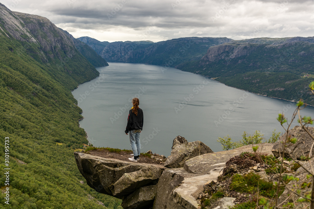 Woman overlooking lysefjorden from a scenic point similar to prædikestolen