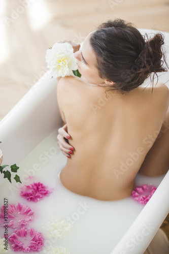 Perfect woman bathing with flowers and milk