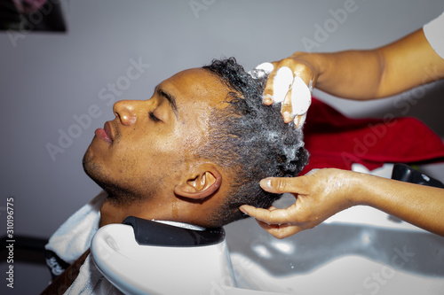 Hairdresser washing hair to her handsome client. Barber at work. Man at barbershop.