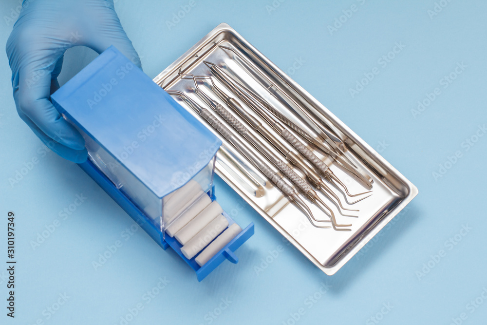 Dentist's hand with box and set of metal dental instruments for teeth dental care Dentist's hand with box and set of metal dental instruments for teeth dental care