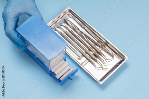 Dentist's hand with box and set of metal dental instruments for teeth dental care