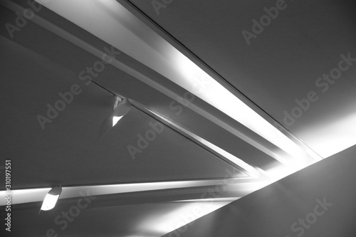 Double exposure of ceiling with backlit girders and spot lights. Abstract architecture fragment. Modern office building interior with polygonal white concrete elements. Diagonal geometric composition.