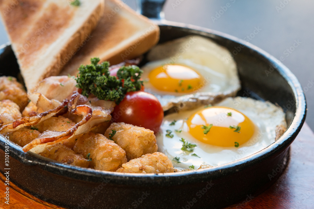 Scrambled egg skillet with toast,hash brown,tomatoes on a black background and wooden plate, Scrambled egg skillet with toast,hash brown,tomatoes on a black background and wooden plate,