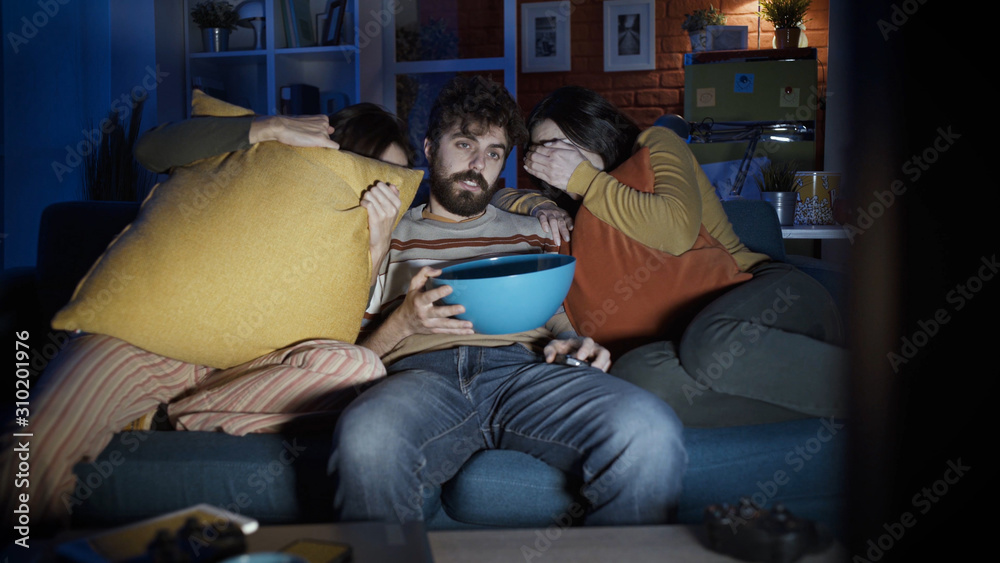 Friends watching scary horror movies on TV at home