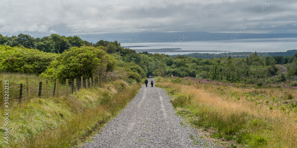 People walking on dirt road passing through field, Grange, County Sligo, Ireland People walking on dirt road passing through field, Grange, County Sligo, Ireland