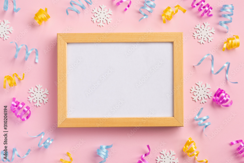 Photo frame. Holiday, winter concept. Colorful serpentine and golden stars, on pink  background. Flat lay, top view, copy space.