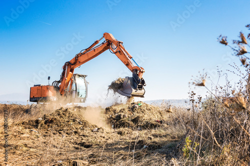 Excavator clears land for construction of a highway photo