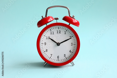 Red alarm clock on turquoise background shows