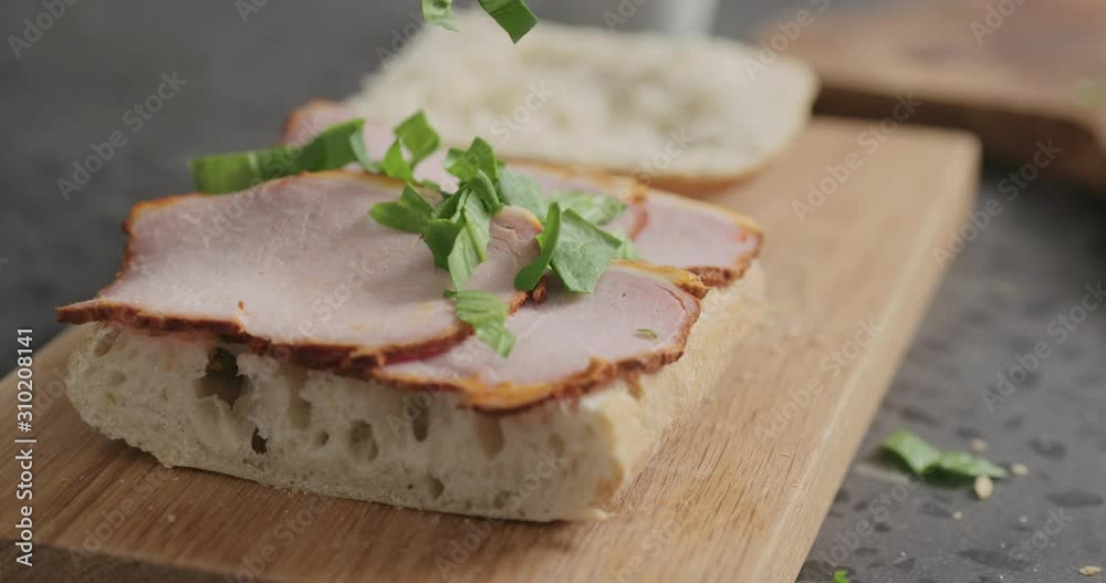Slow motion man making sandwich add chopped spinach