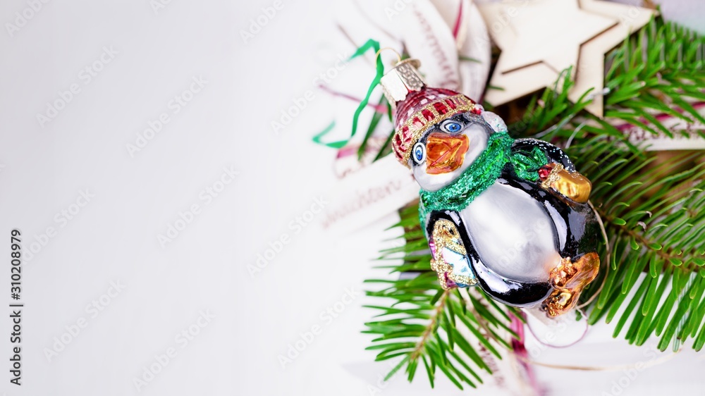 Merry Christmas and Happy New Year. Christmas tree branch and funny vintage penguin on a white wooden background. Top view, copy space, 16:9