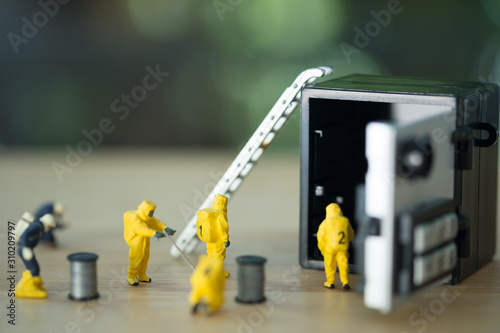 Miniature technical team in hazmat suits are monitoring contaminants in safety box