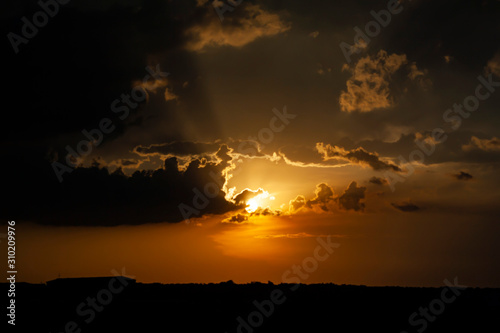 dark clouds on the background of the rays of the sun at sunset