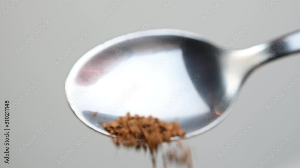 spoon pours coffee into a cup on a gray background spoon pours coffee into a cup on a gray background