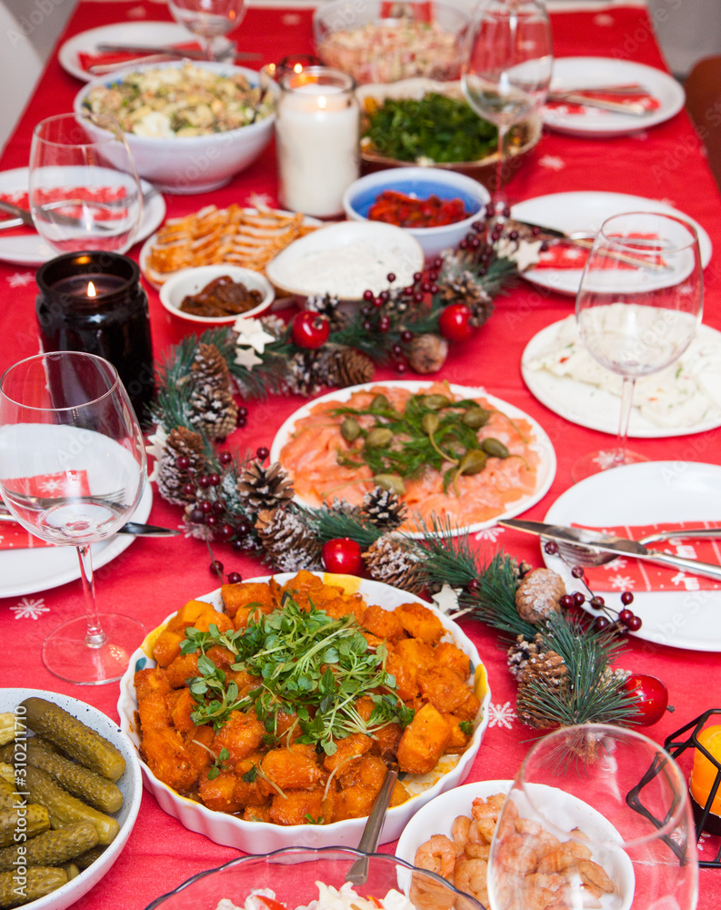 Served table with christmas decoration, red napkin, garland and candles. 