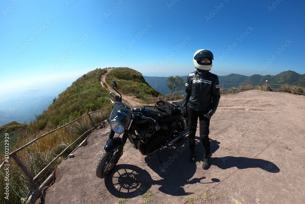 Biker woman journey by motorcyclewith peak of mountains scenery background. Biker lifestyle relaxing in freedom with modern vintage design motorbike. Success in your life concept. Biker woman journey by motorcyclewith peak of mountains scenery background. Biker lifestyle relaxing in freedom with modern vintage design motorbike. Success in your life concept.