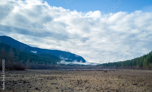 Dramatic aerial Photography of Rattlesnake lake surrounded by tree trumps and clouds reflecting off the shallow lake in the fall with the fog covered mountains in near distance in Washington State