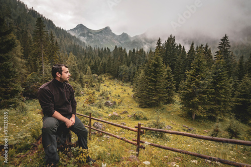 Lonley man in front of a remote mountainscape on a rainy day photo