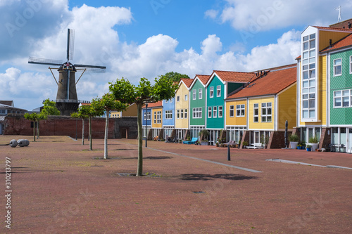Farbenfrohe Häuser im Hafen von Hellevoetsluis/Niederlande mit der historischen Windmühle im Hintergrund photo