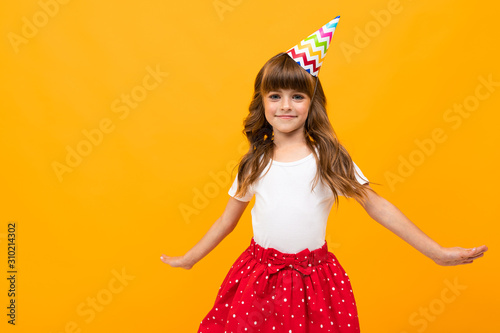 happy girl with a holiday cap in a skirt on a yellow background