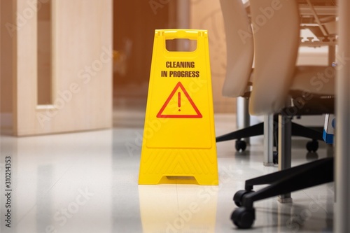 yellow sign of caution reserve cleaning on the wet floor in office room