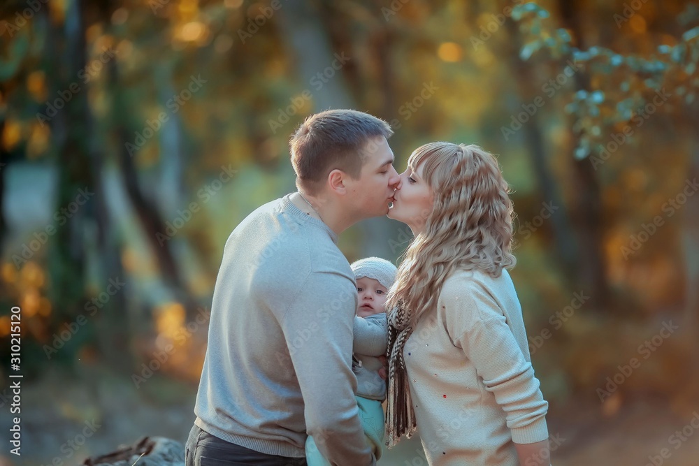 Family outdoors feel the love of their child hugging and kissing him in the autumn forest on a walk. Family outdoors feel the love of their child hugging and kissing him in the autumn forest on a walk.