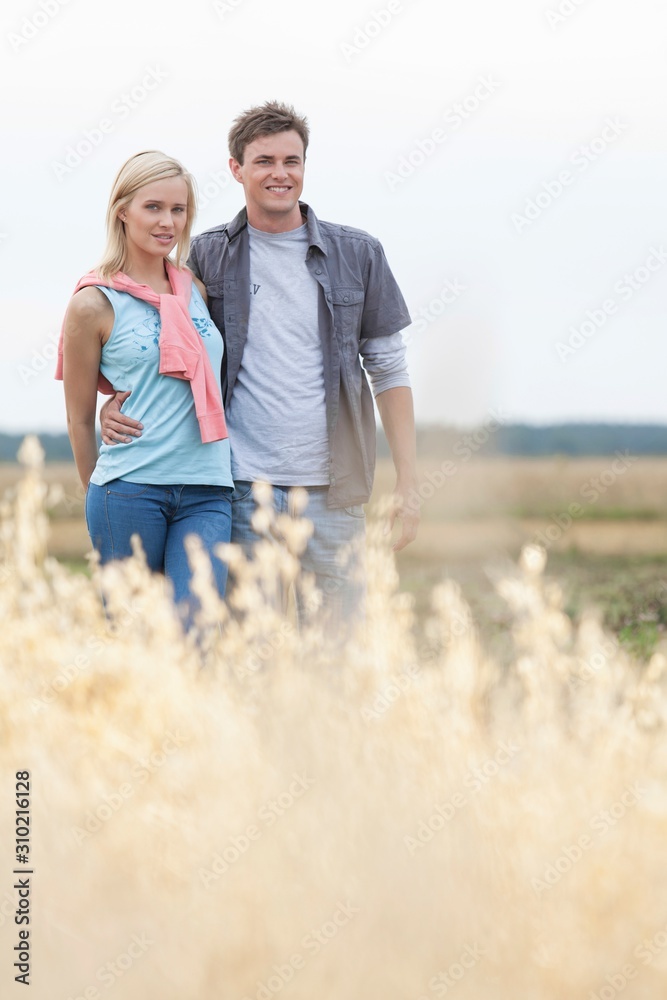 Portrait of young couple standing at field Portrait of young couple standing at field