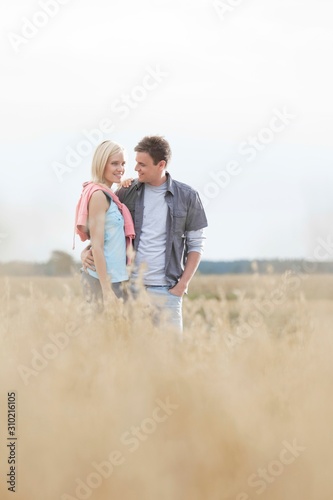 Happy loving young couple standing together at field
