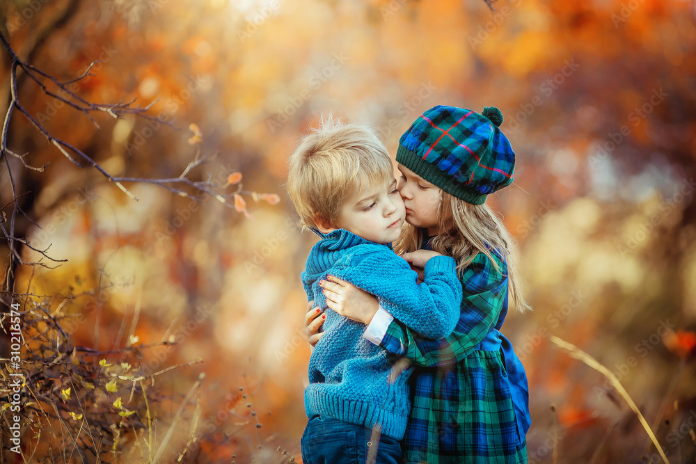 Children dressed in warm autumn clothes hug and smile in the red and yellow forest. Children dressed in warm autumn clothes hug and smile in the red and yellow forest.