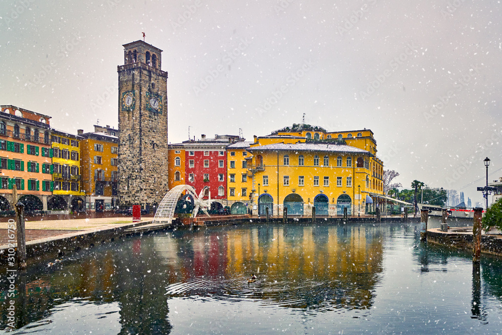 Fototapeta premium View of the beautiful Lake Garda surrounded by mountains,Riva del Garda town and Garda lake in the winter time on a snowy day,Trentino Alto Adige region