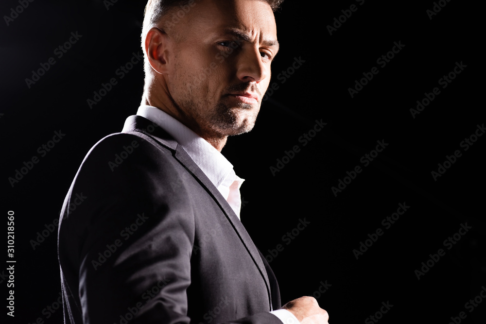 Side view of confident businessman looking at camera isolated on black Side view of confident businessman looking at camera isolated on black