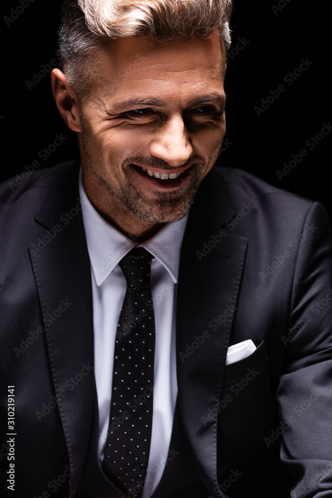 Smiling businessman in suit looking away isolated on black Smiling businessman in suit looking away isolated on black