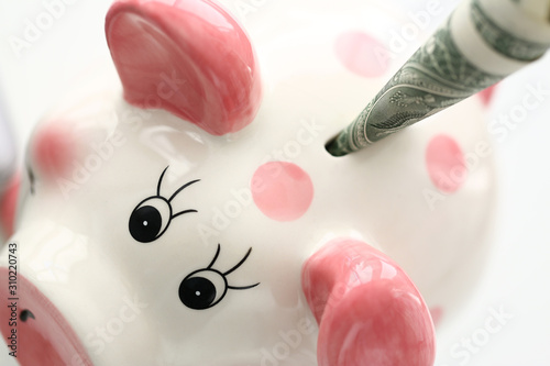 Funny pink piggybank holding one us dollar banknote