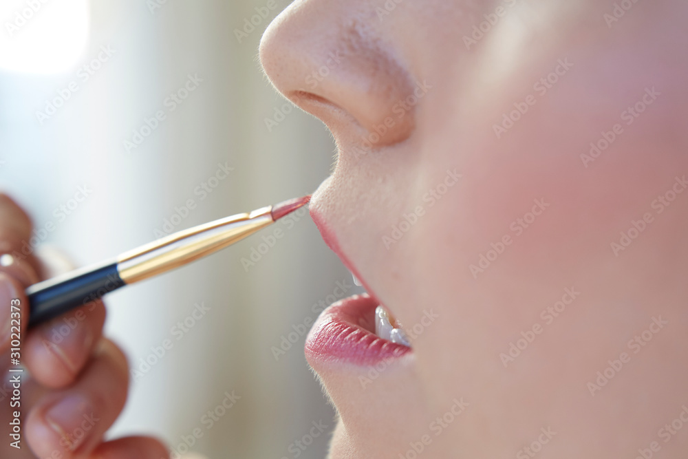 Woman painting her lips. Lipstick make up. Close up picture. 