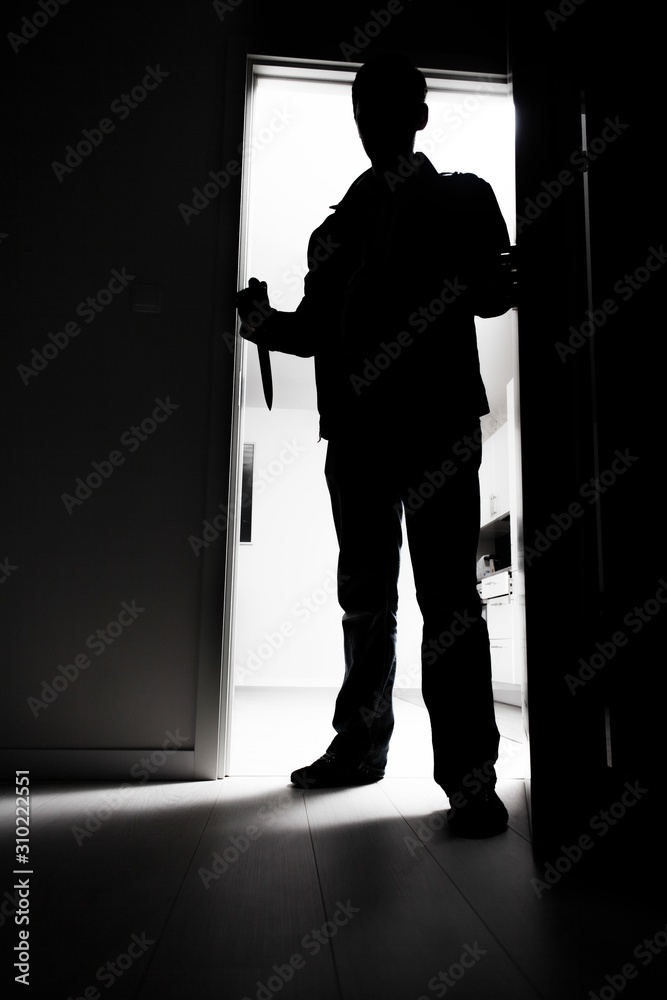 Full-length of thief with knife entering into dark room