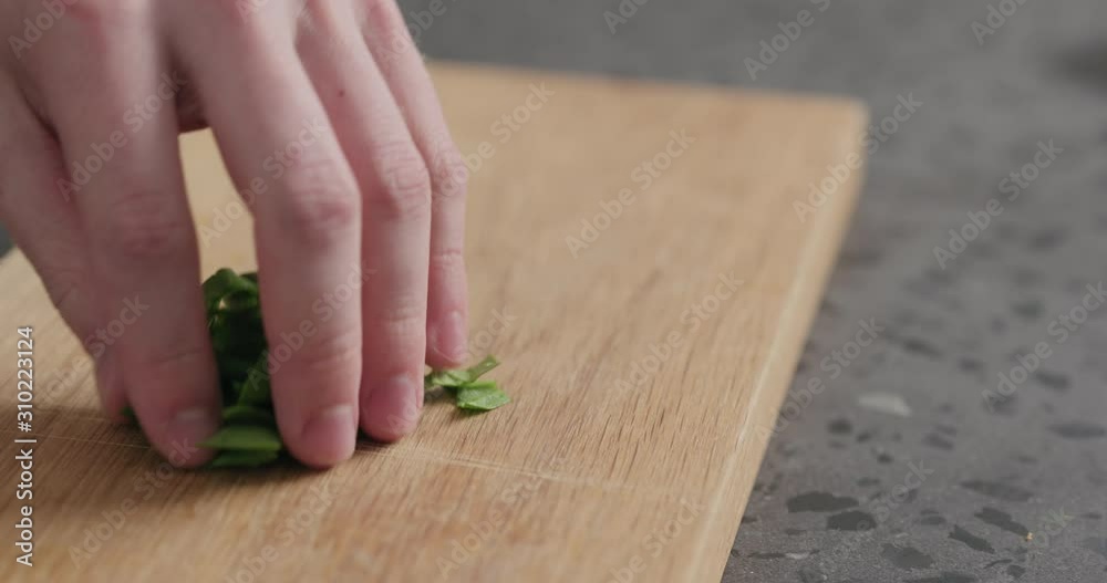 Slow motion man take chopped fresh spinach leaves on oak cutting board Slow motion man take chopped fresh spinach leaves on oak cutting board