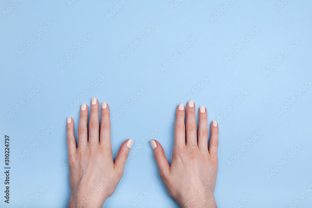 Beautiful female hands with a classic matte manicure lie on the table. Place for your text. Beautiful female hands with a classic matte manicure lie on the table. Place for your text.