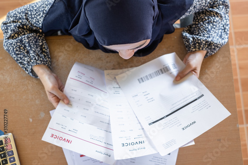 Top view of Muslim woman wearing hijab reading the invoice documents. photo